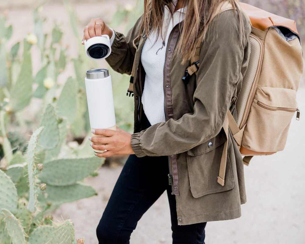 Woman wearing a backpack and holding a thermos