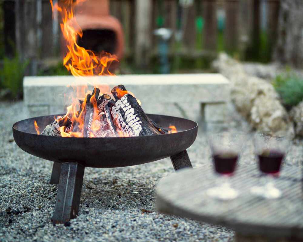 Outdoor fire pit next to a small table featuring two glasses of wine